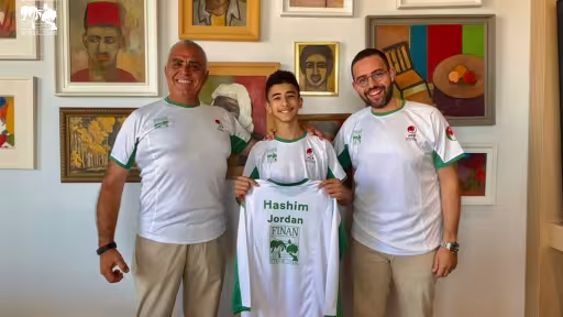 Climber Hashim Adel Jafar holding his Finan-sponsored jersey with Finan Group representatives