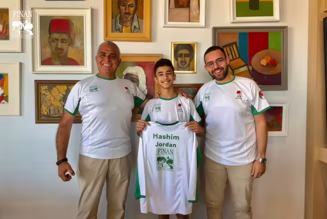 Climber Hashim Adel Jafar holding his Finan-sponsored jersey with Finan Group representatives